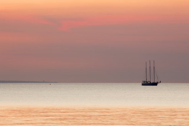 One lonely yacht against a smoky dry season sunset sky (Fannie Bay)